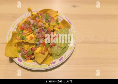 Deliziosa scorpacciata di nachos con formaggio e Guacamole sul tavolo di legno Foto Stock