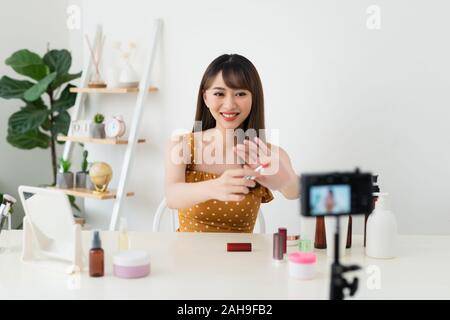 Che cosa è questo. Piuttosto giovane donna seduta nella parte anteriore della fotocamera durante la sperimentazione dei cosmetici Foto Stock