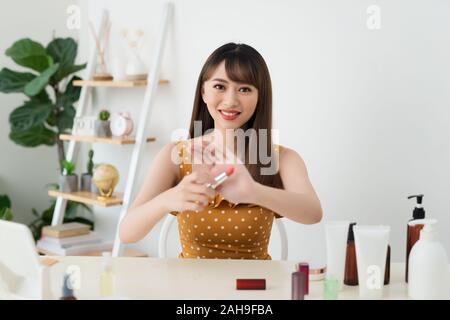 Che cosa è questo. Piuttosto giovane donna seduta nella parte anteriore della fotocamera durante la sperimentazione dei cosmetici Foto Stock