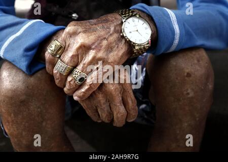 Vicino la foto di una coppia di mani con pelle rugosa di un vecchio uomo che indossa gioielli Foto Stock