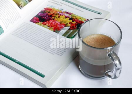 Una tazza di caffè e libro fotografico su sfondo bianco Foto Stock
