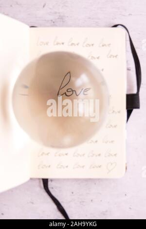 Una lente di cristallo sfera con amore la parola riflessione Foto Stock