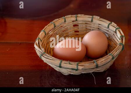 Le uova nel paniere di bambù su un tavolo di legno. Foto Stock