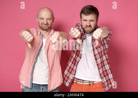 Due uomini, mostrando un brutto segno e antipatia, fare un pollice giù gesto, con una grimace di disapprovazione sui loro volti. Foto Stock