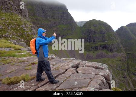 L'uomo prese le foto nelle vicinanze delle scogliere di un Chioch sulla montagna scozzese Corbett Beinn Bhan, Applecross, nord-ovest, Highlands scozzesi, Scotland, Regno Unito. Foto Stock