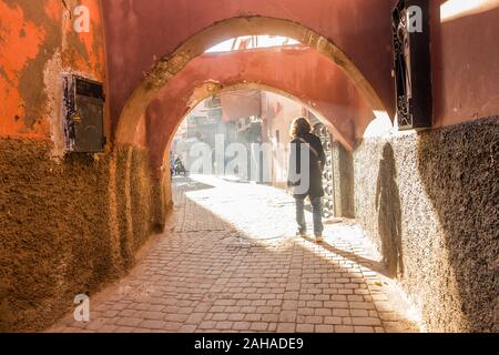 Donna cammina in una strada piena di fumo nella Medina di Marrakech, Marocco. Foto Stock