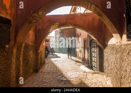 Donna cammina in una strada piena di fumo nella Medina di Marrakech, Marocco. Foto Stock