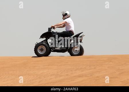 30.03.2018, Dubai, Dubai, Emirati Arabi Uniti - Uomo aziona un quad bike attraverso il deserto. 00S180330D061CAROEX.JPG [modello di rilascio: sì, proprietà rele Foto Stock