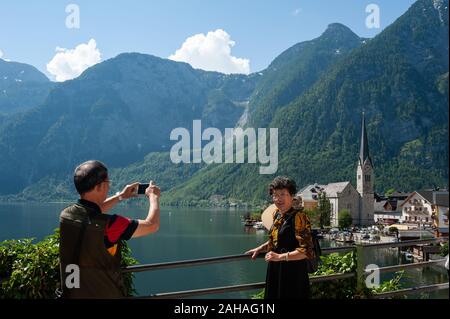 18.06.2019, Hallstatt, Austria superiore, Austria - turisti cinesi di scattare foto sopra il lago Hallstaetter vedere con la chiesa e le montagne in backgr Foto Stock