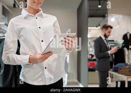 Felice giovane femmina consulente di boutique lo scrolling attraverso nuovi elementi online Foto Stock