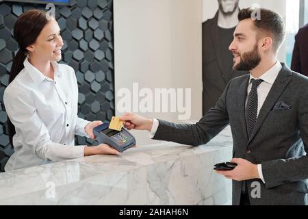 Felice giovane ed elegante uomo con carta di credito per il pagamento la macchina dal contatore Foto Stock