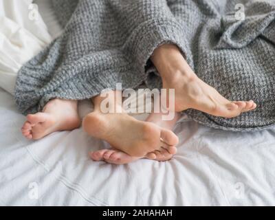 Giovane dormire nel letto. Vista ravvicinata di un piede di un paio. Amore e relazioni concetto. Foto Stock