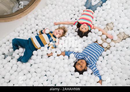 Gruppo di carino piccolo interculturale bambini in informale divertendosi in palloncini Foto Stock