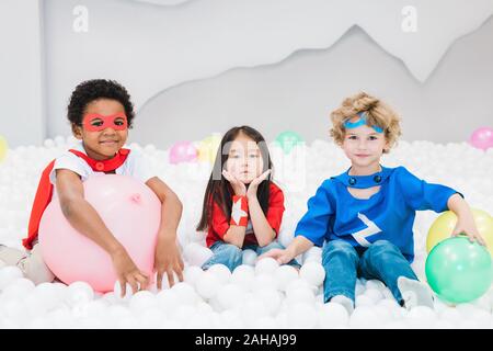 Adorabili poco amici interculturale in costumi giocando in camera per bambini Foto Stock