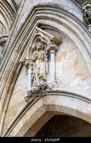 Statua di Pietra di angelo annunziante holding alcuni fiori nella mano sinistra, la Cattedrale di Salisbury, Salisbury, Wiltshire, Inghilterra Foto Stock