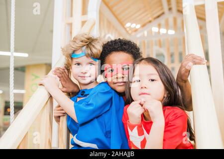 Intercultural piccoli amici in costume seduto sulla scalinata nella parte anteriore della fotocamera Foto Stock