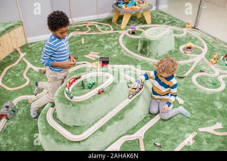 Due piccoli interculturale ragazzi di trascorrere del tempo sulla area di gioco dei bambini centro Foto Stock