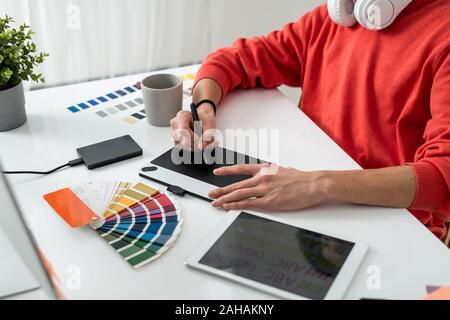 Le mani del contemporaneo designer freelance con lo stilo sulla tavoletta grafica Foto Stock