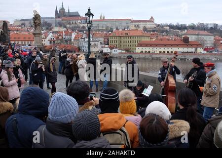 Praga, Repubblica Ceca. 27 Dic, 2019. Musicisti di strada la riproduzione di musica insieme con la sua band sul Ponte Carlo a Praga nella Repubblica Ceca. Il Castello di Praga in background. Il Ponte Carlo a Praga è una delle principali destinazioni turistiche della Repubblica ceca. Credito: Slavek Ruta/ZUMA filo/Alamy Live News Foto Stock