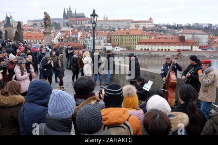Praga, Repubblica Ceca. 27 Dic, 2019. Musicisti di strada la riproduzione di musica insieme con la sua band sul Ponte Carlo a Praga nella Repubblica Ceca. Il Castello di Praga in background. Il Ponte Carlo a Praga è una delle principali destinazioni turistiche della Repubblica ceca. Credito: Slavek Ruta/ZUMA filo/Alamy Live News Foto Stock