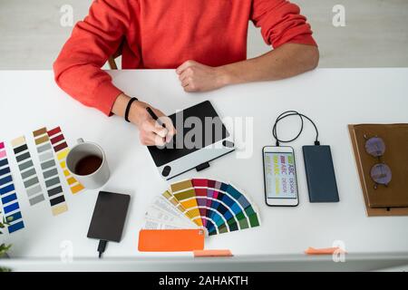 Le mani del giovane maschio web designer con lo stilo durante lavori di ritocco da scrivania Foto Stock
