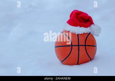 La pallacanestro indossando un cappello da Babbo Natale sulla neve anche durante l inverno Foto Stock