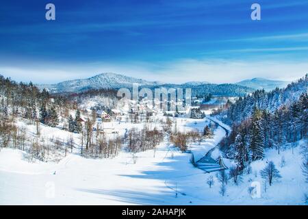 Inverno in Croazia, paesaggio di campagna in inverno, vista panoramica della cittadina di Lokve sotto la neve nella regione di Gorski kotar Foto Stock