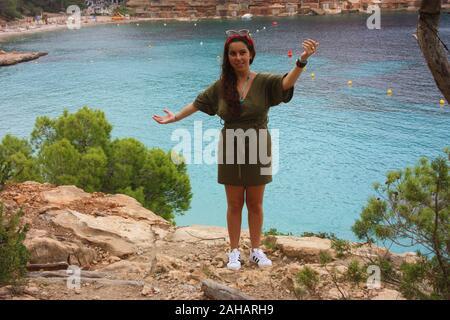 Ragazza caucasica sulla scogliera della cala saladeta gode di vacanze estive nella natura selvaggia delle isole baleari godendo in Ibiza Foto Stock