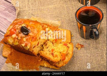 Un affettato fatta in casa torta di Natale su una tavola di legno e una tazza di tè su un tavolo ricoperto con un panno homespun Foto Stock