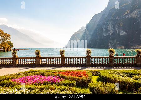 Lago di Garda promenade con aiuole fiorite con la crescita e la fioritura delle piante, classic recinzione in pietra costruito sul bordo con vasi da fiori con rigogliosi fl Foto Stock