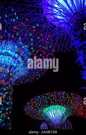 Illuminato gigante artificiale alberi Super sostare di fronte alla Marina Bay Sands, a giardini dalla Baia di Singapore Foto Stock