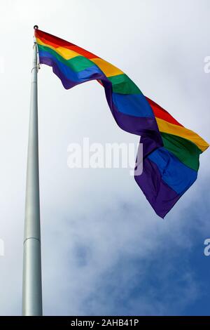 Basso angolo vista della bandiera arcobaleno sul pennone contro la metà cielo nuvoloso nel quartiere Castro di San Francisco, Stati Uniti d'America Foto Stock