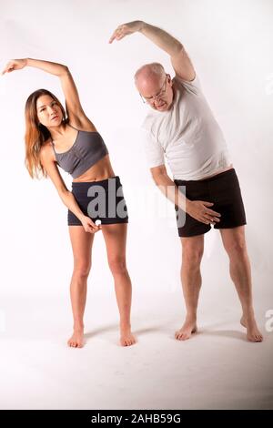 Dicembre 2018- Coppia guy essendo mostrato base posizione Yoga da un esperto persona più giovane Foto Stock