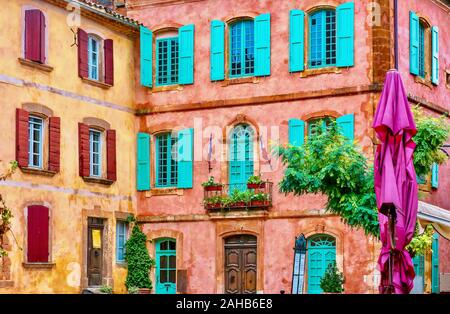 Belle, colorate facciate di edifici realizzati da localmente minato ocra, nel pittoresco villaggio francese di Roussillon, Provenza. Foto Stock