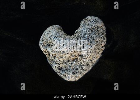 Bianco a forma di cuore sulla pietra di sabbia nera vulcanica. Foto Stock