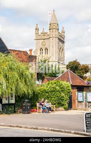 Amersham, Inghilterra - 22 agosto 2019: la gente seduta a parlare su un banco di pubblico. St Marys chiesa è in background. Foto Stock
