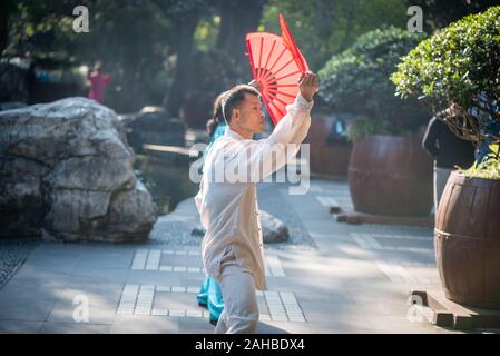 Chengdu, nella provincia di Sichuan, in Cina - Ott 31, 2018 : l uomo e la donna pratica il Tai Chi con ventole di rosso nella mattinata con la gente del parco. Foto Stock