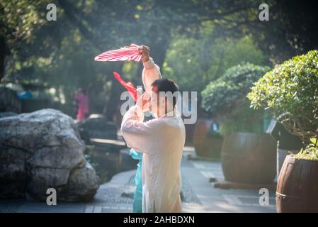 Chengdu, nella provincia di Sichuan, in Cina - Ott 31, 2018 : l uomo e la donna pratica il Tai Chi con ventole di rosso nella mattinata con la gente del parco. Foto Stock