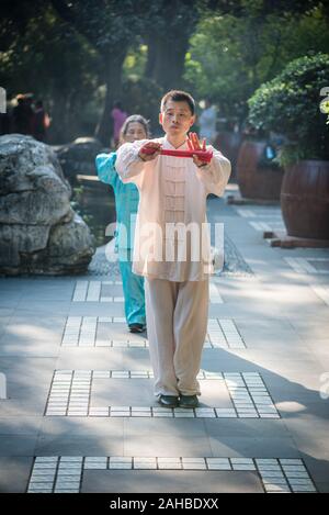 Chengdu, nella provincia di Sichuan, in Cina - Ott 31, 2018 : l uomo e la donna pratica il Tai Chi con ventole di rosso nella mattinata con la gente del parco. Foto Stock