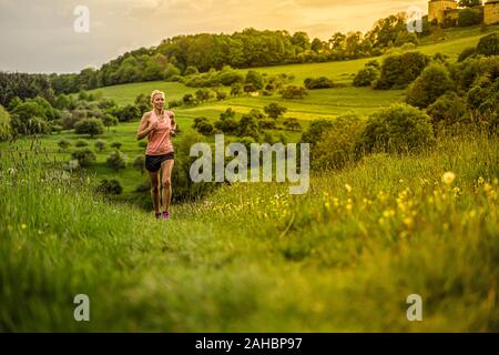 Una donna di mezza età corre attraverso le colline Foto Stock