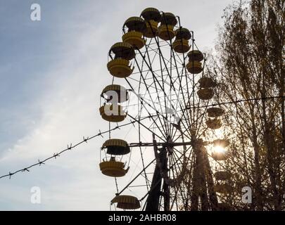 Filo spinato e cabine antica giostra ruota in un parco giochi abbandonato di Chernobyl in Ucraina in autunno Foto Stock