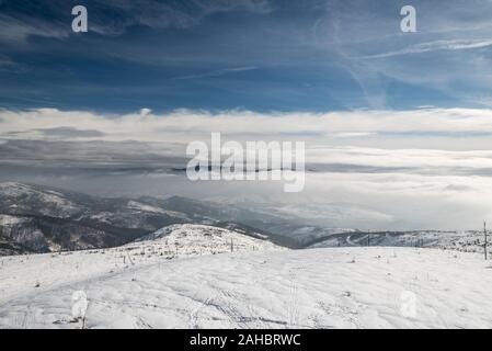 Vista da Barania Gora hill in Beskid Slaski montagne in Polonia durante il giorno in inverno con nebbia e cielo blu con nuvole sopra Foto Stock