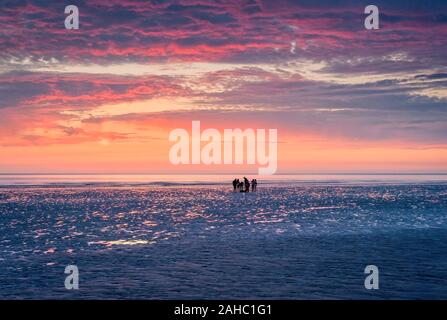 Silhouette di un gruppo di persone con il cielo del tramonto su Westward ho! Beach, North Devon, Regno Unito Foto Stock