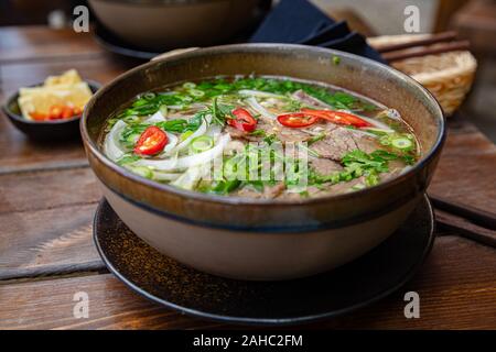 Close-up di fresca zuppa Pho in ciotola serviti al tavolo Foto Stock