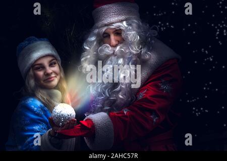 Una fanciulla di neve donna sorge accanto alla Santa nelle braccia di una sfera incandescente Foto Stock