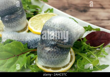 Aringhe in salamoia con insalata mista su tavola in legno Foto Stock