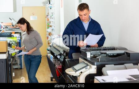 Team di professionisti opera su una apparecchiatura di stampa Foto Stock