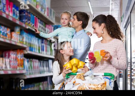 Bellissimi i genitori con due bambini acquisto di yogurt alla frutta e budino Foto Stock