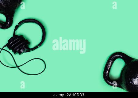 Foto sportive. Kettlebells e manubri di menta su sfondo verde. Appartamento laico, vista dall'alto, copia dello spazio. Foto Stock