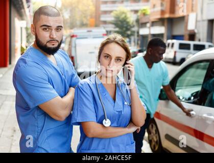 Positivo personale efficiente e paramedici con kit di primo soccorso andando a chiamata da ambulanza Foto Stock